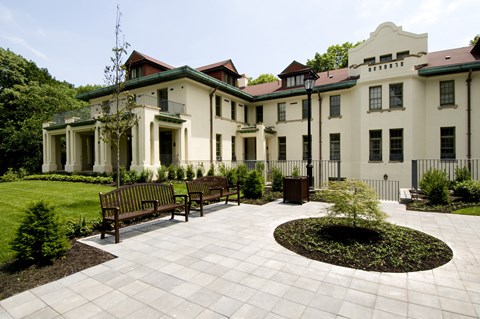 a courtyard in front of a large white building with benches