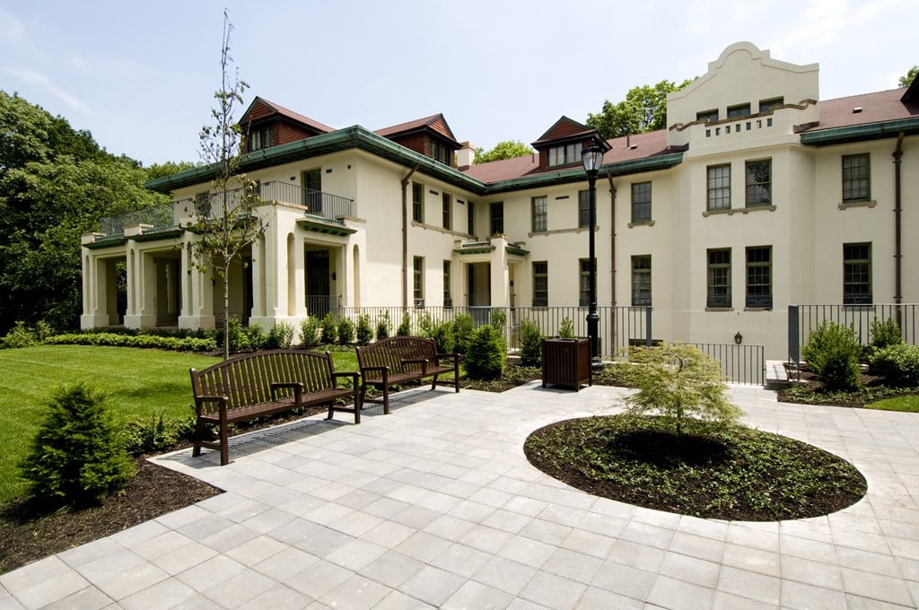a courtyard in front of a large white building with benches