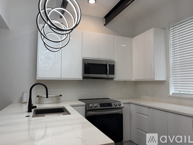 A modern kitchen with white cabinets and a black stove top.