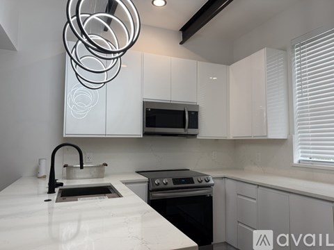 A modern kitchen with white cabinets and a black stove top.