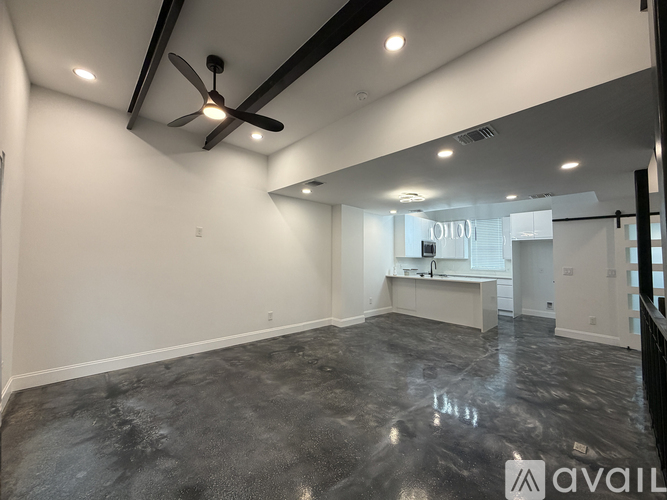 A spacious room with a ceiling fan and a large island in the middle.