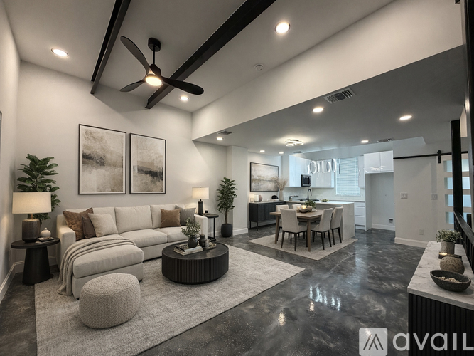 A modern living room with a large sofa, a coffee table, and a dining area in the background.