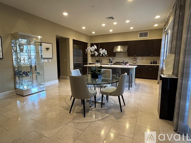 A modern kitchen with a glass dining table and chairs.