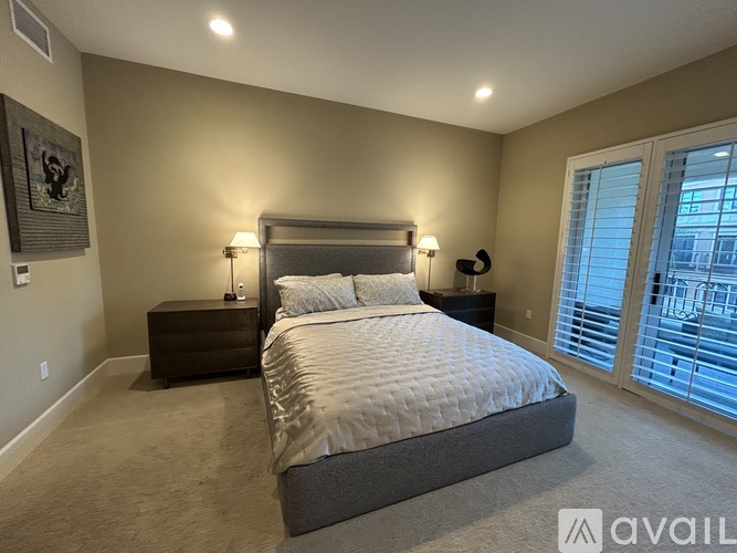 A bedroom with a large bed and a window with blinds.