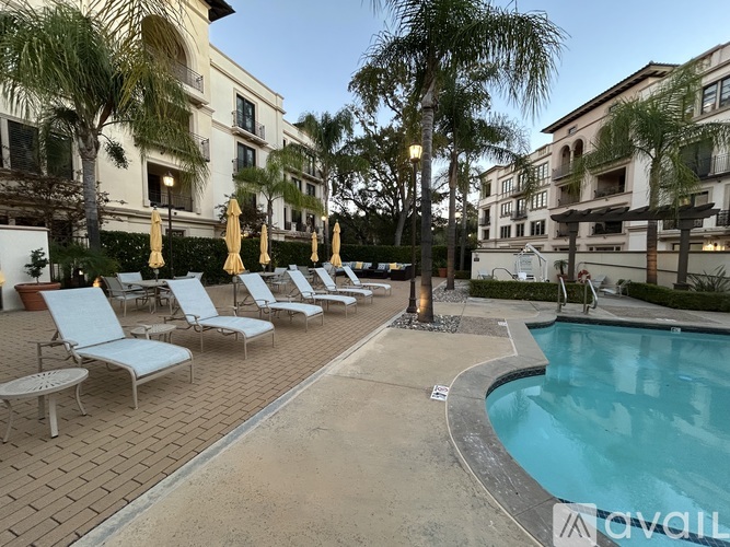 A pool area with lounge chairs and umbrellas in front of a building.