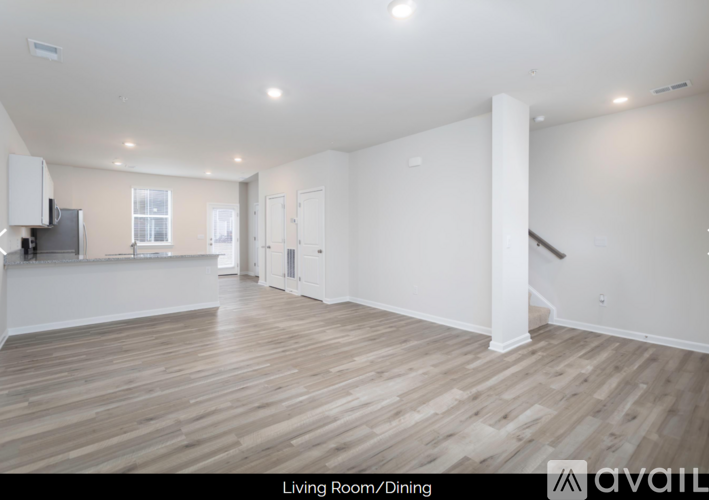 A spacious living room with wooden flooring and white walls.