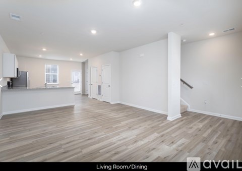 A spacious living room with wooden flooring and white walls.