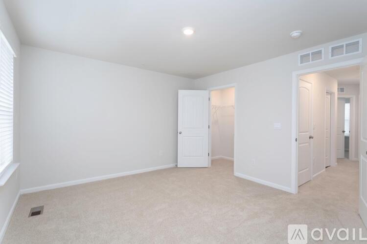 A spacious room with white walls and carpeted floor.