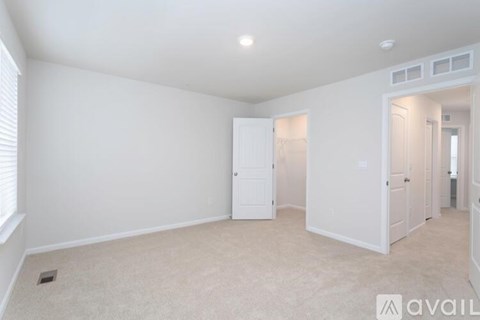 A spacious room with white walls and carpeted floor.