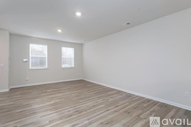 A room with wooden flooring and two windows.