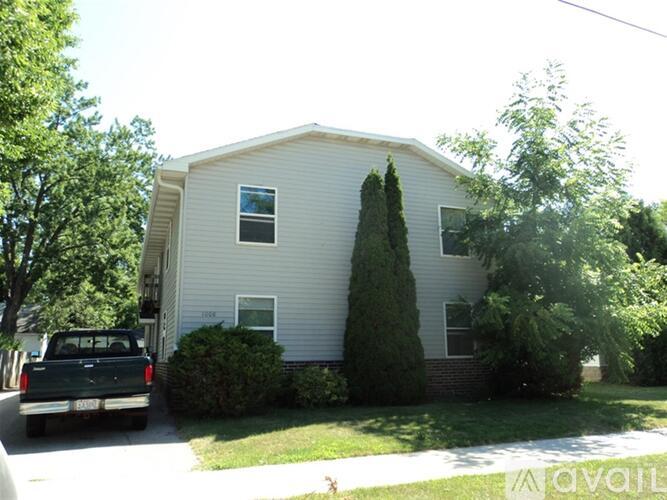 A house with a white siding and a green lawn.