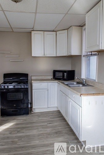 A kitchen with white cabinets and a black stove top oven.