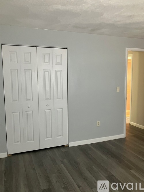A room with a white door and a grey wall.