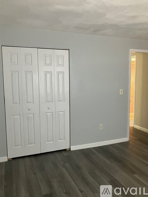 A room with a white door and a grey wall.