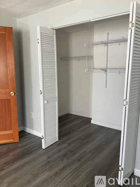 A white closet with a door open and shelves on the wall.