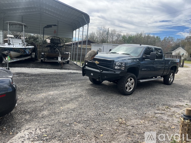 A black Chevrolet Silverado is parked in a gravel lot.