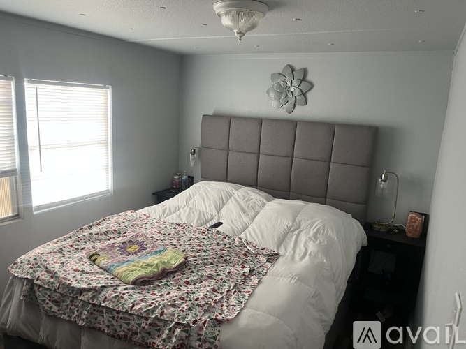A bedroom with a bed covered in a floral comforter and a decorative flower on the headboard.