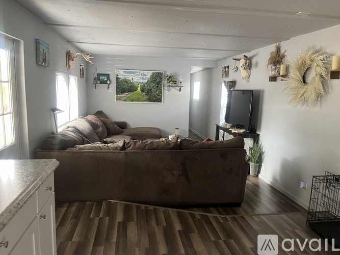 A living room with a brown couch and a painting of a mountain scene on the wall.
