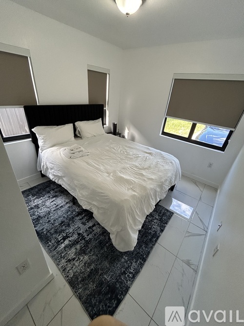 A bedroom with a large bed and a window with blinds.