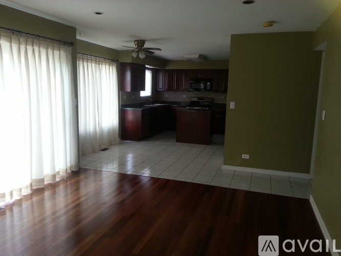 A kitchen with a fan on the ceiling and a dining table with chairs.
