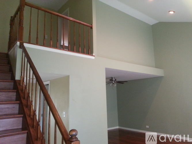 A staircase with a wooden banister and a fan in the corner of a room.