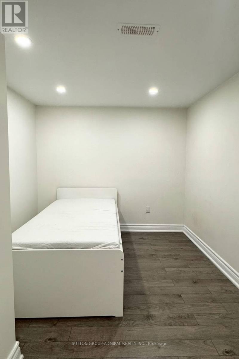 A bedroom with a white bed and wooden flooring.