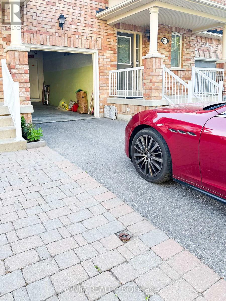 A red car is parked in front of a brick house.