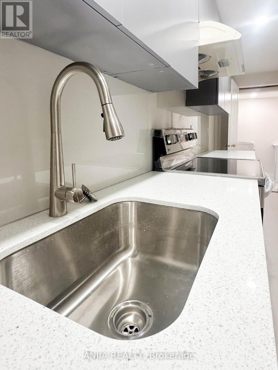 A modern kitchen with a stainless steel sink and faucet.
