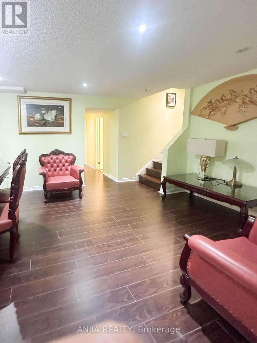 A living room with a red chair and a wooden floor.