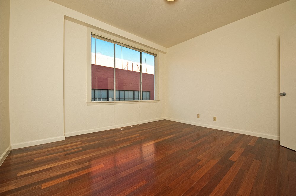 an empty living room with wood floors and a window