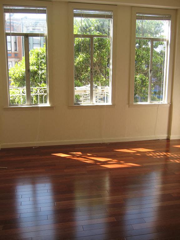 a living room with a wood floor and three windows