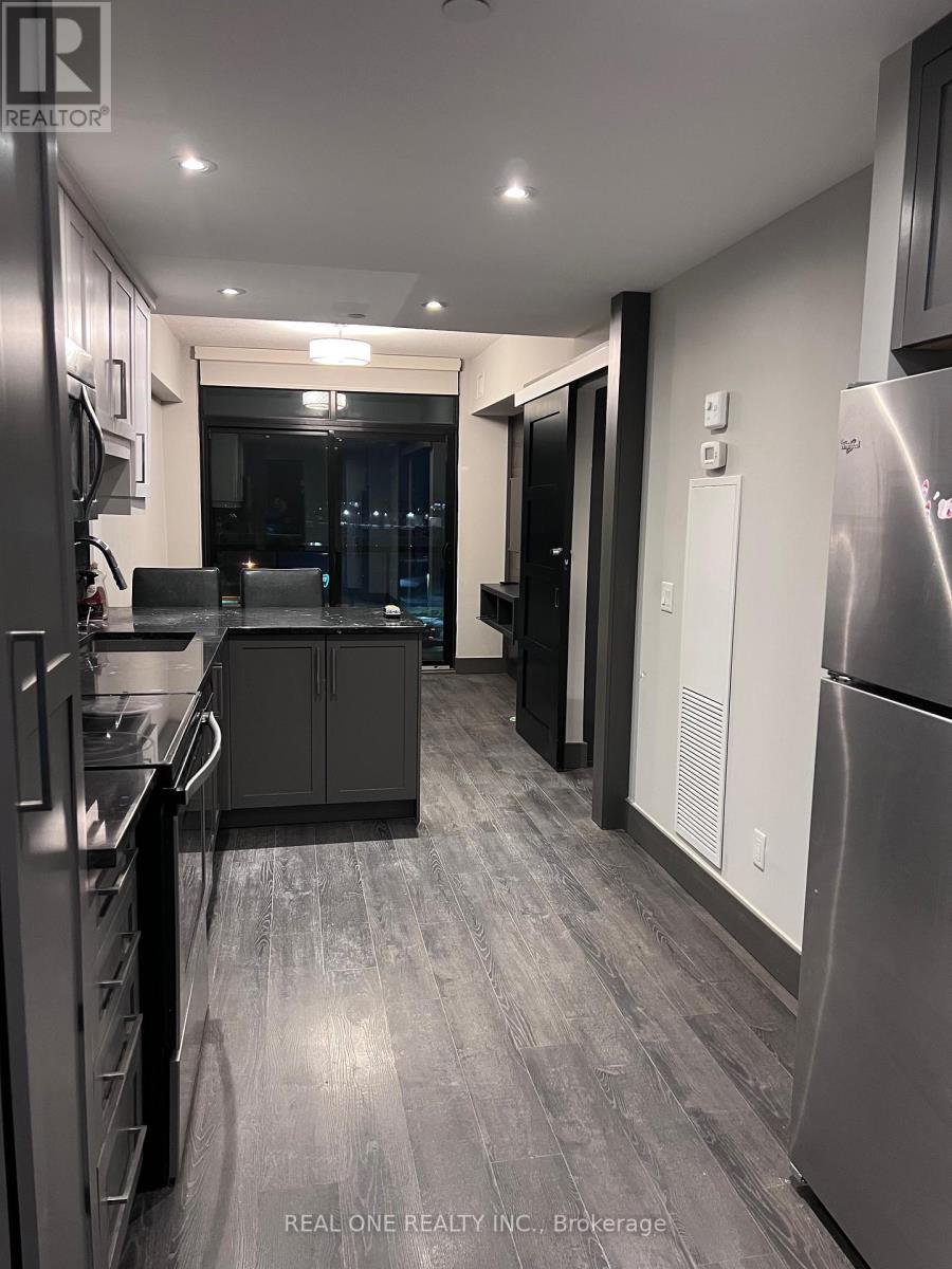A modern kitchen with stainless steel appliances and a wooden floor.