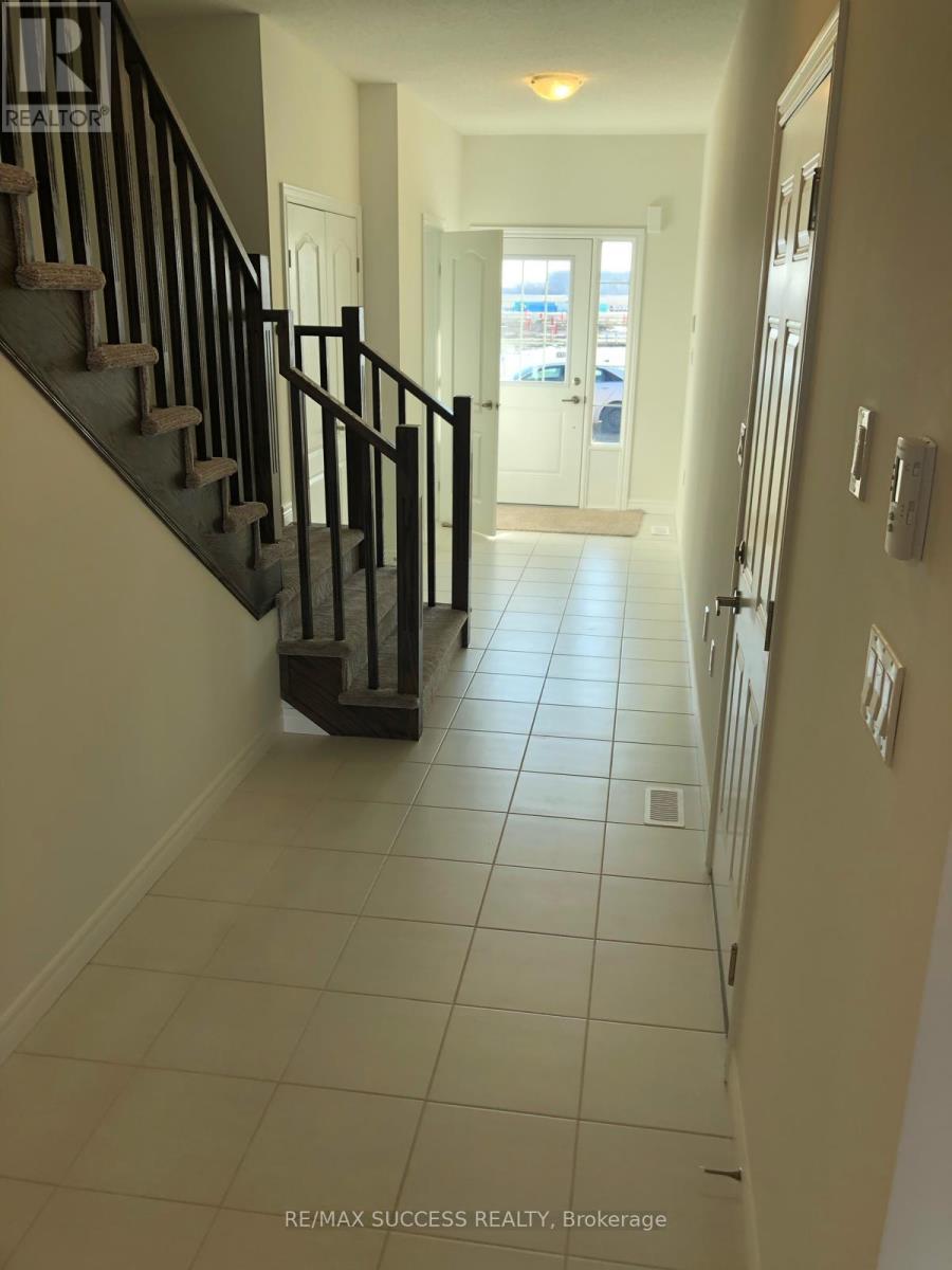 A hallway with a staircase and a door at the end.