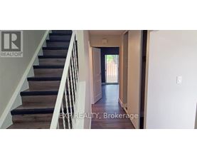 A hallway with a staircase leading to a door.