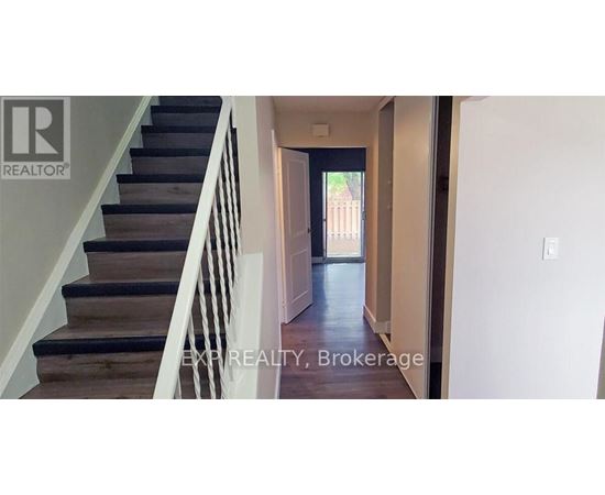 A hallway with a staircase leading to a door.