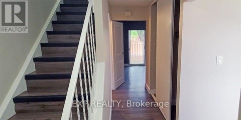A hallway with a staircase leading to a door.