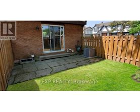 A backyard with a wooden fence and a brick house.