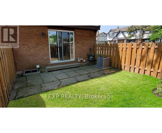 A backyard with a wooden fence and a brick house.