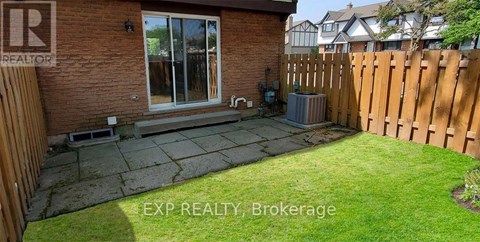 A backyard with a wooden fence and a brick house.