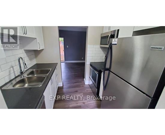 A kitchen with a stainless steel refrigerator and a sink.