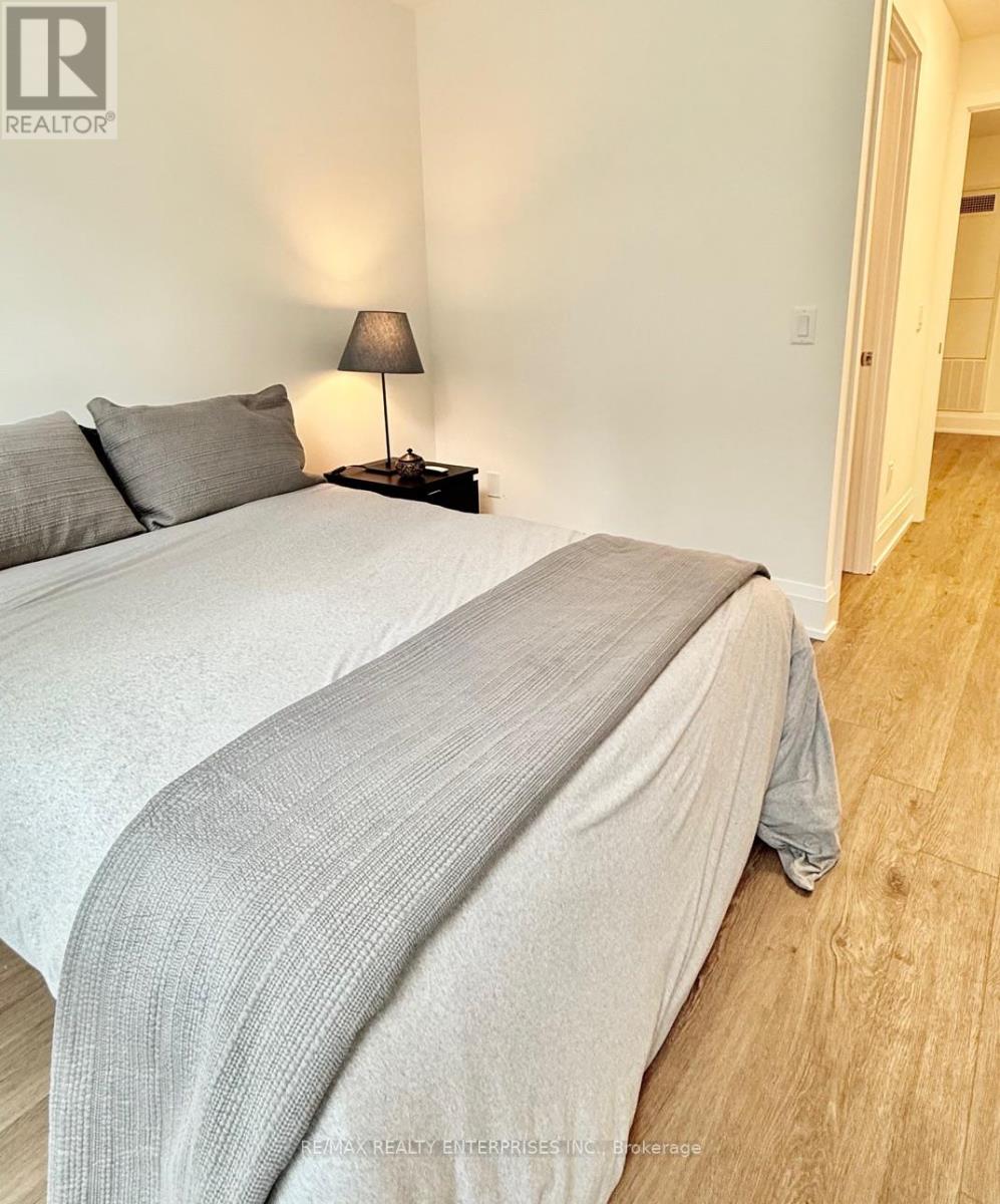 A bedroom with a bed, pillows, and a lamp.