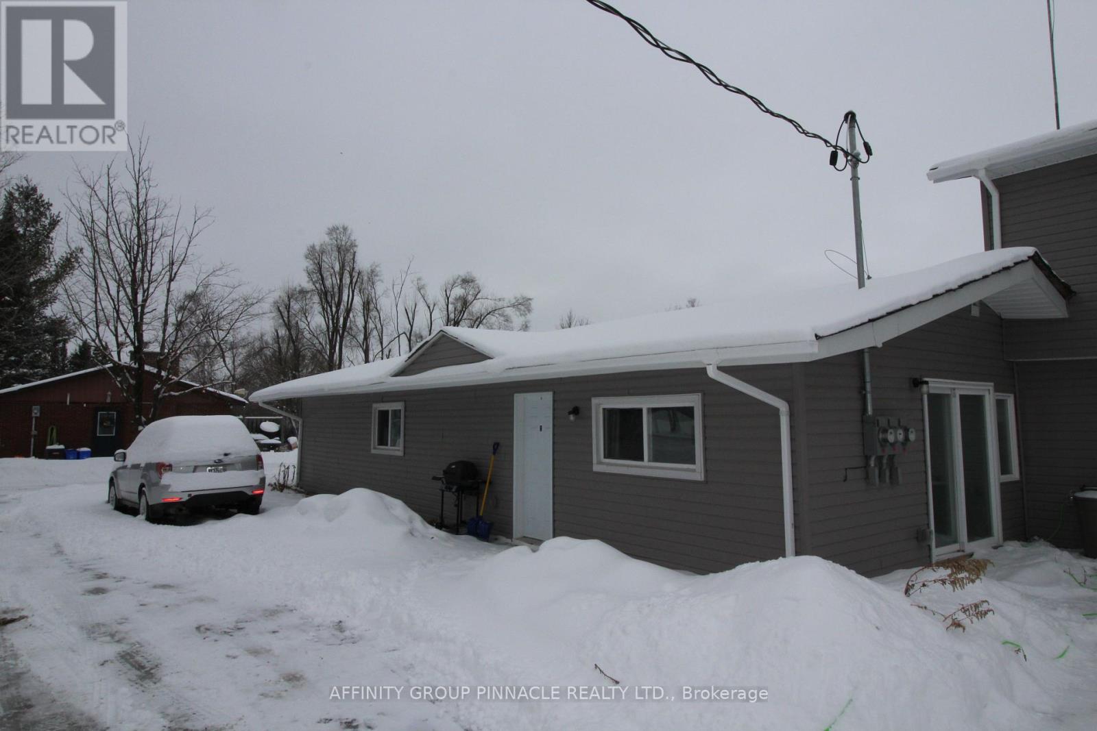 A house with a car covered in snow in front of it.