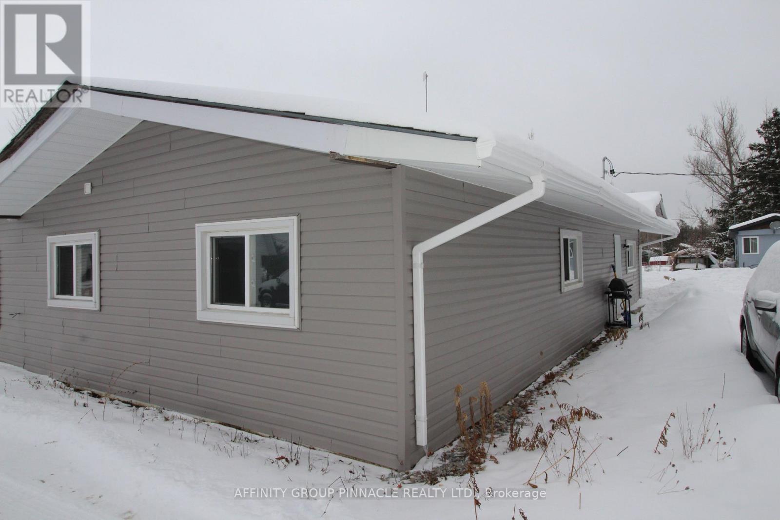 A house with a grey siding and a white roof is shown in the image.