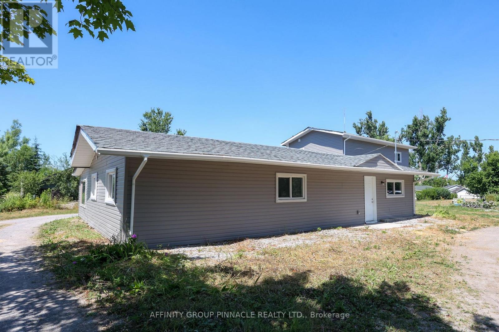 A house with a grey siding and a white door is for sale.