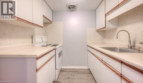 A small, white kitchen with a sink and a refrigerator.