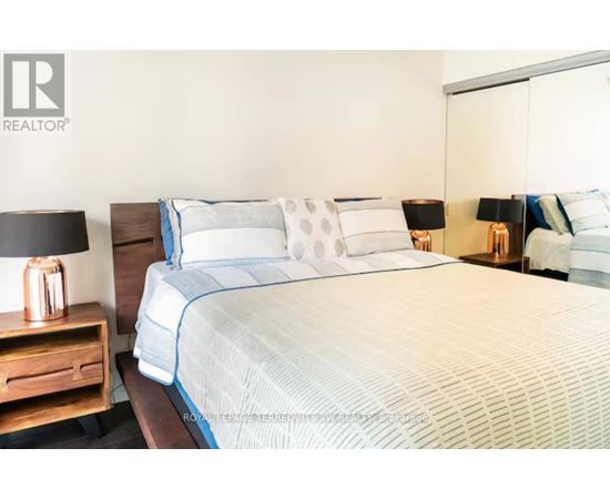 A bed with a white and blue comforter and pillows in a bedroom.