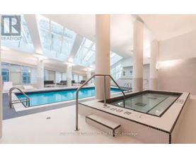 A swimming pool inside a building with a glass ceiling.