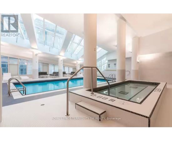 A swimming pool inside a building with a glass ceiling.