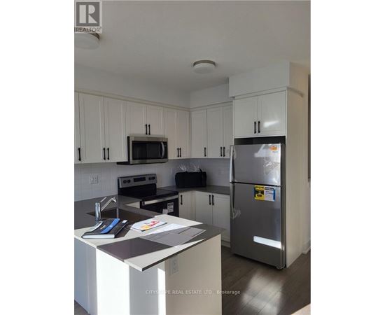 A kitchen with white cabinets and a refrigerator.