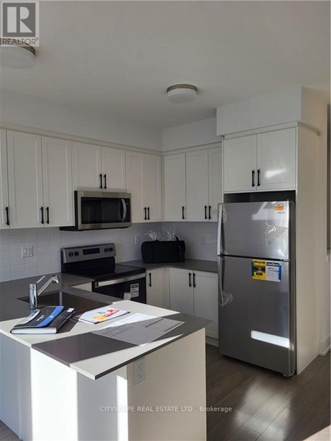 A kitchen with white cabinets and a refrigerator.